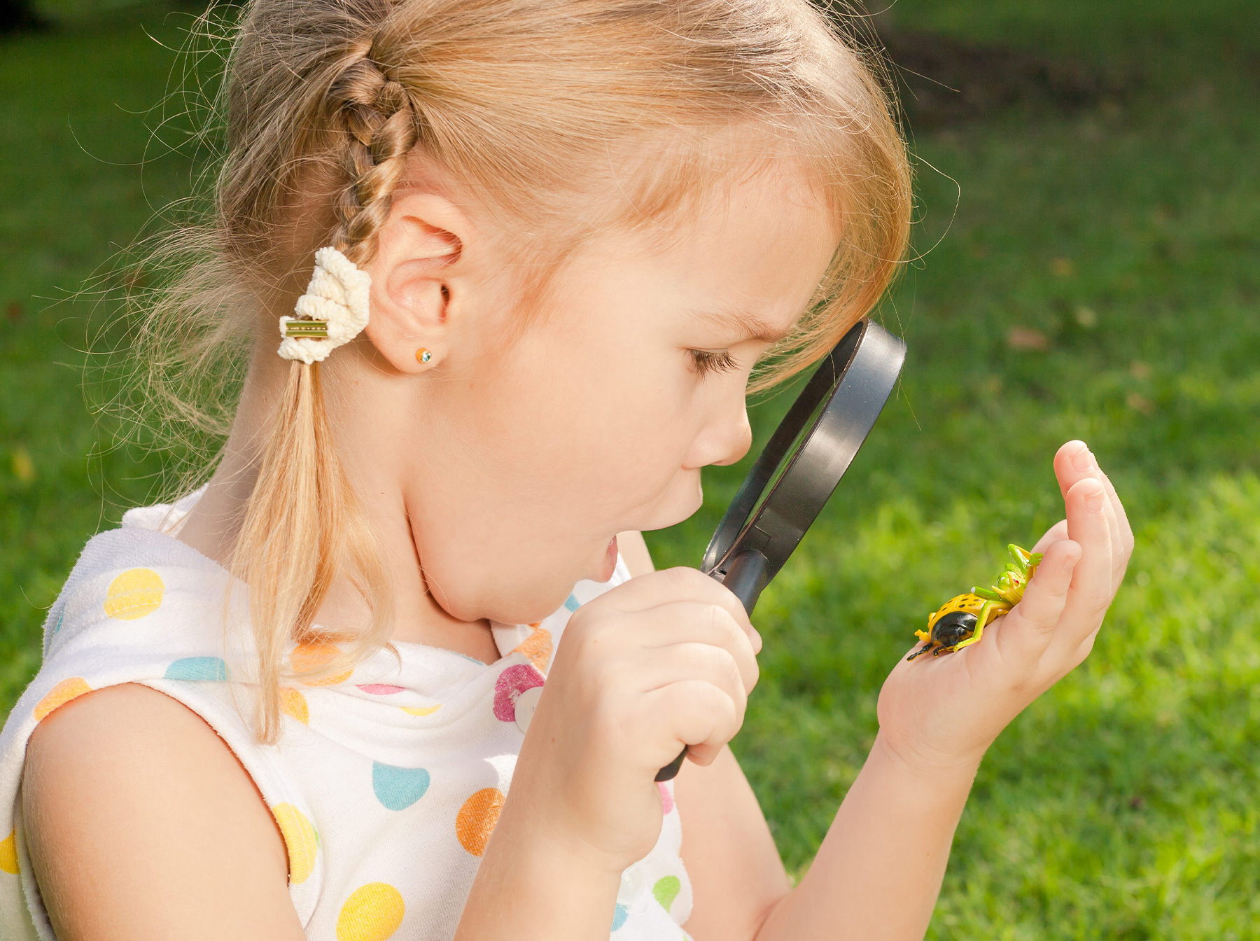 child using magnifying glass outdoors